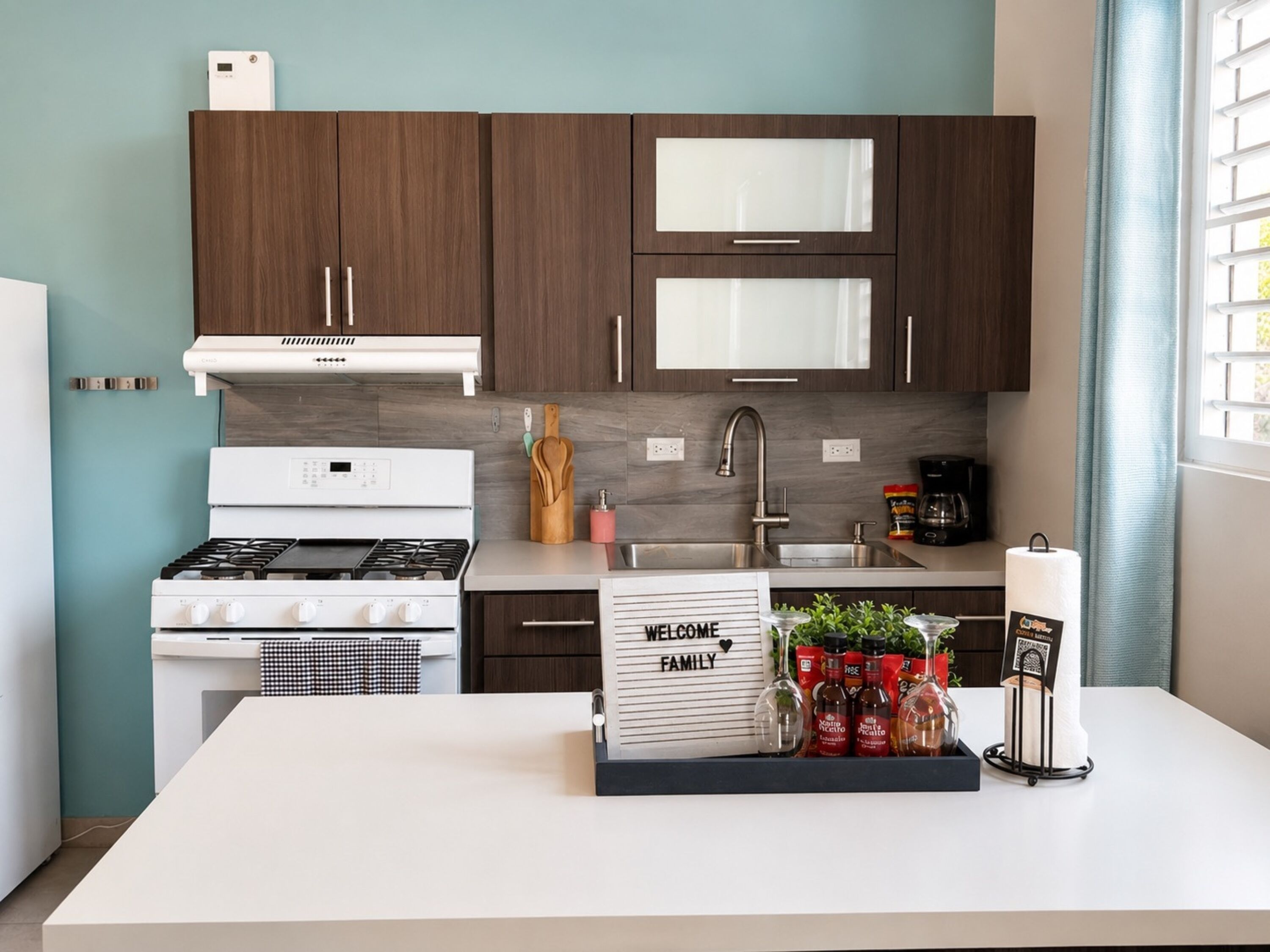 Une cuisine moderne avec des meubles de couleur bois foncé, une cuisinière blanche et un évier en acier inoxydable.