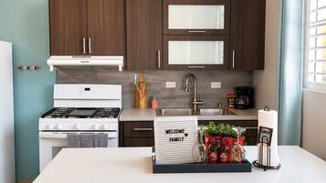 Una cocina moderna con gabinetes de madera oscura, una estufa blanca y un lavamanos de acero inoxidable.
