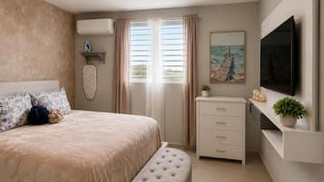 Un dormitorio con cama, televisor, cómoda y un cuadro.