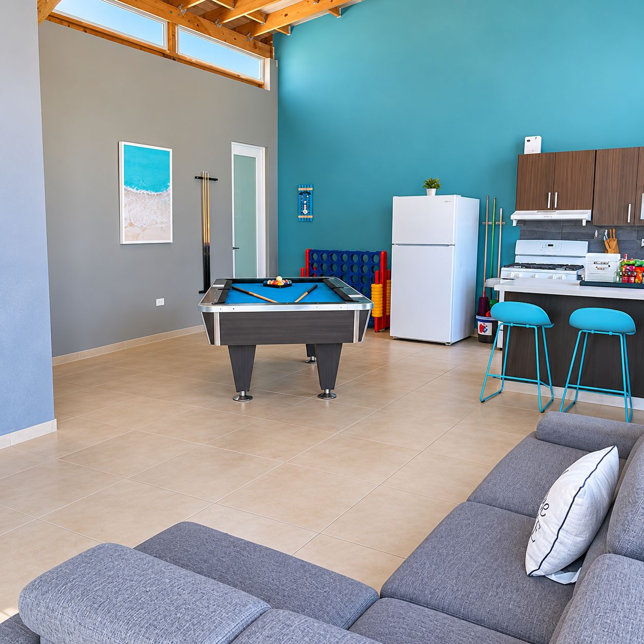 Un espacio de estar moderno con mesa de billar, sofá y zona de cocina.