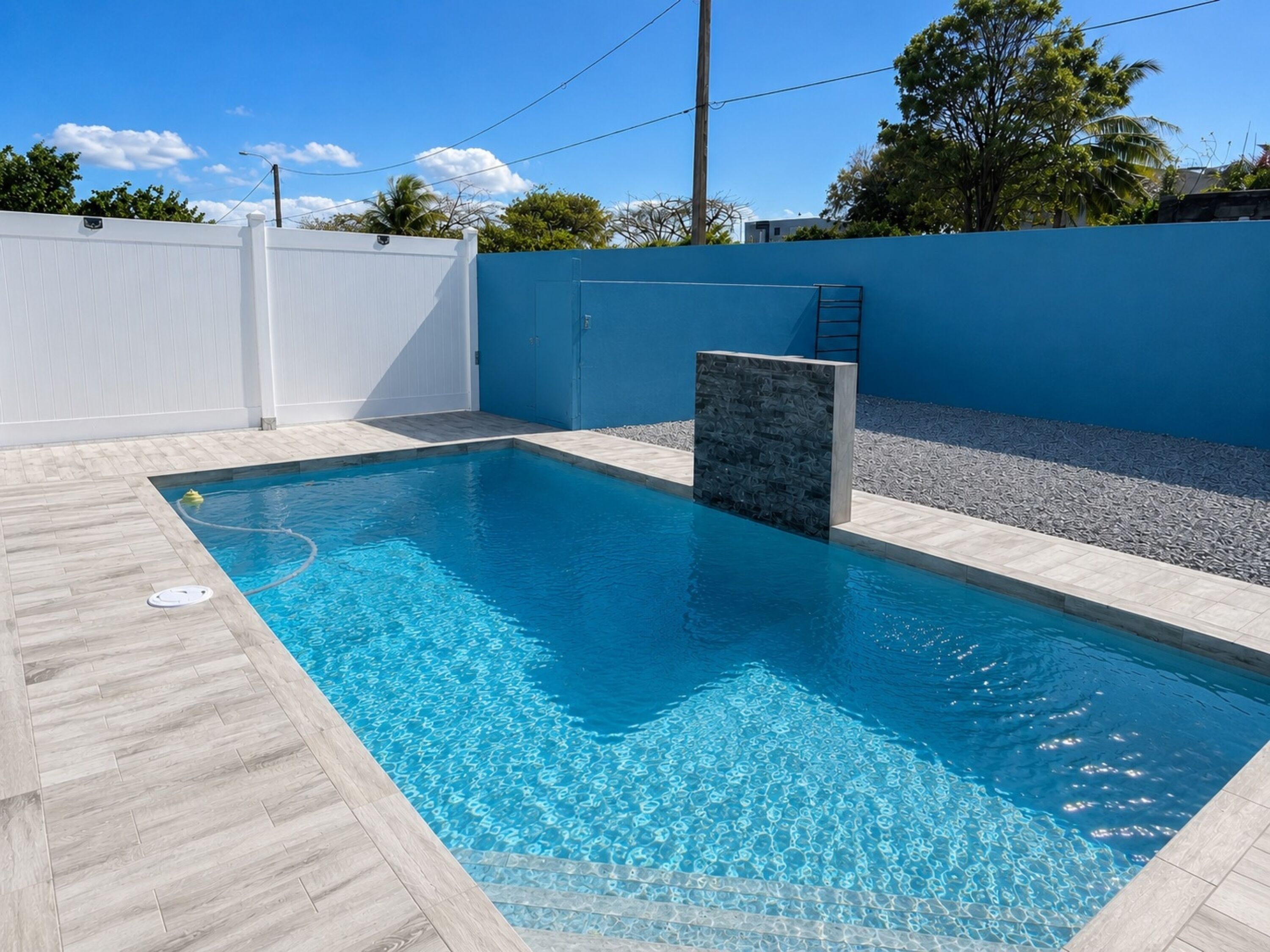 Une piscine rectangulaire à l’eau d’un bleu limpide, entourée d’une terrasse carrelée aux couleurs claires.