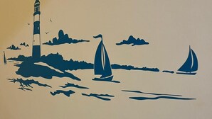 Majakan siluetti tyynellä merellä, ja sen edessä purjehtivia purtaveneitä.