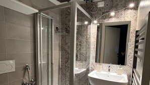 Moderni kylpyhuone, jossa on lasiseinällä varustettu suihku, wc, pesuallas ja peili.