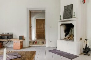Habitació amb una llar de foc, una porta que dona a una altra estança i una taula amb equipament d'àudio.