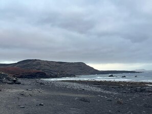 En stenstrand med ett berg i bakgrunden.