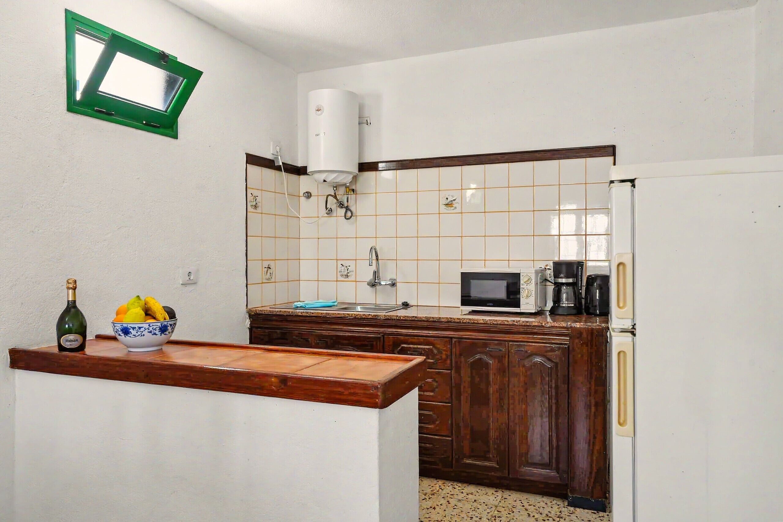 Una cocina equipada con microondas, cafetera y calentador de agua.
