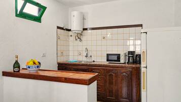 Una cocina equipada con microondas, cafetera y calentador de agua.