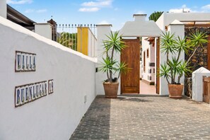 Eine Villa namens 'Villa Buen Lugar' mit befestigtem Zugang, Topfpflanzen und einer Holztür.