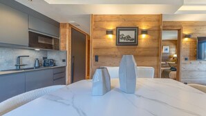 A modern kitchen with a marble countertop, wooden wall paneling, and a framed picture above the sink. - Walking distance—historic center—sleeps 6 (Megève)