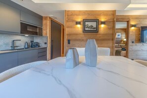 A modern kitchen with a marble countertop, wooden wall paneling, and a framed picture above the sink. - Walking distance—historic center—sleeps 6 (Megève)