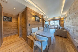 Ein modernes Interieur mit Holzwänden, einem Esstisch, Stühlen und einer Couch.