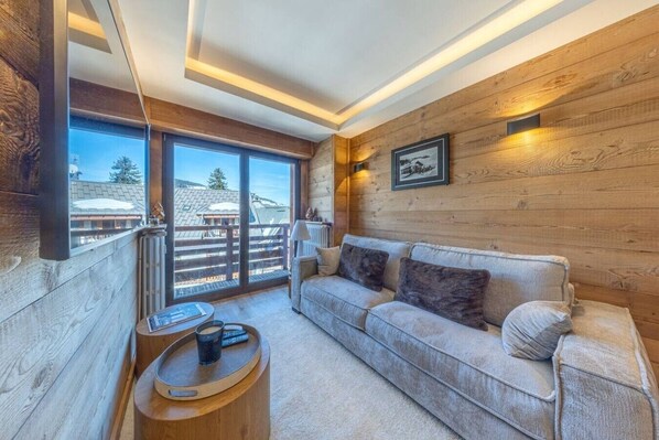 Ein gemütliches Wohnzimmer mit einer Couch, einem Couchtisch und einem großen Fenster mit Blick auf eine verschneite Landschaft.