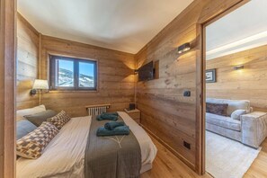 Ein Zimmer mit Holzwänden, einem Bett, einem Nachttisch, einem Fernseher und einem Sofa.