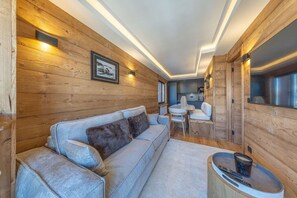 Ein gemütliches Blockhauss-Interieur mit einer Couch, einem Esstisch und einer Küchenzeile.