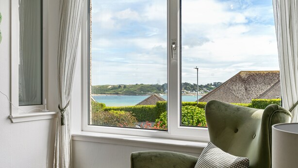 A room with a view of a coastal landscape through a large window, a green armchair, and a lamp. - 22 Treverbyn Road  - Spacious Home with amazing estuary views (Padstow)
