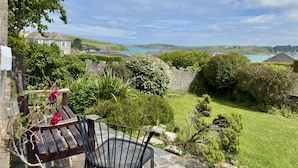 A garden with a bench, a stone wall, and a view of the sea and hills. - 22 Treverbyn Road  - Spacious Home with amazing estuary views (Padstow)