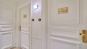 A set of white doors with a nameplate, a light fixture, and a doorbell. - DESIGNED BY ACCLAIMED ARCHITECTS IN THE HEART OF SAINT-GERMAIN- RUE DE GRENELLE (Paris)