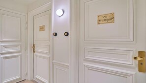 A set of white doors with a nameplate, a light fixture, and a doorbell. - DESIGNED BY ACCLAIMED ARCHITECTS IN THE HEART OF SAINT-GERMAIN- RUE DE GRENELLE (Paris)