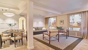 A modern living room with a dining area, a sofa, a patterned rug, and large windows. - DESIGNED BY ACCLAIMED ARCHITECTS IN THE HEART OF SAINT-GERMAIN- RUE DE GRENELLE (Paris)