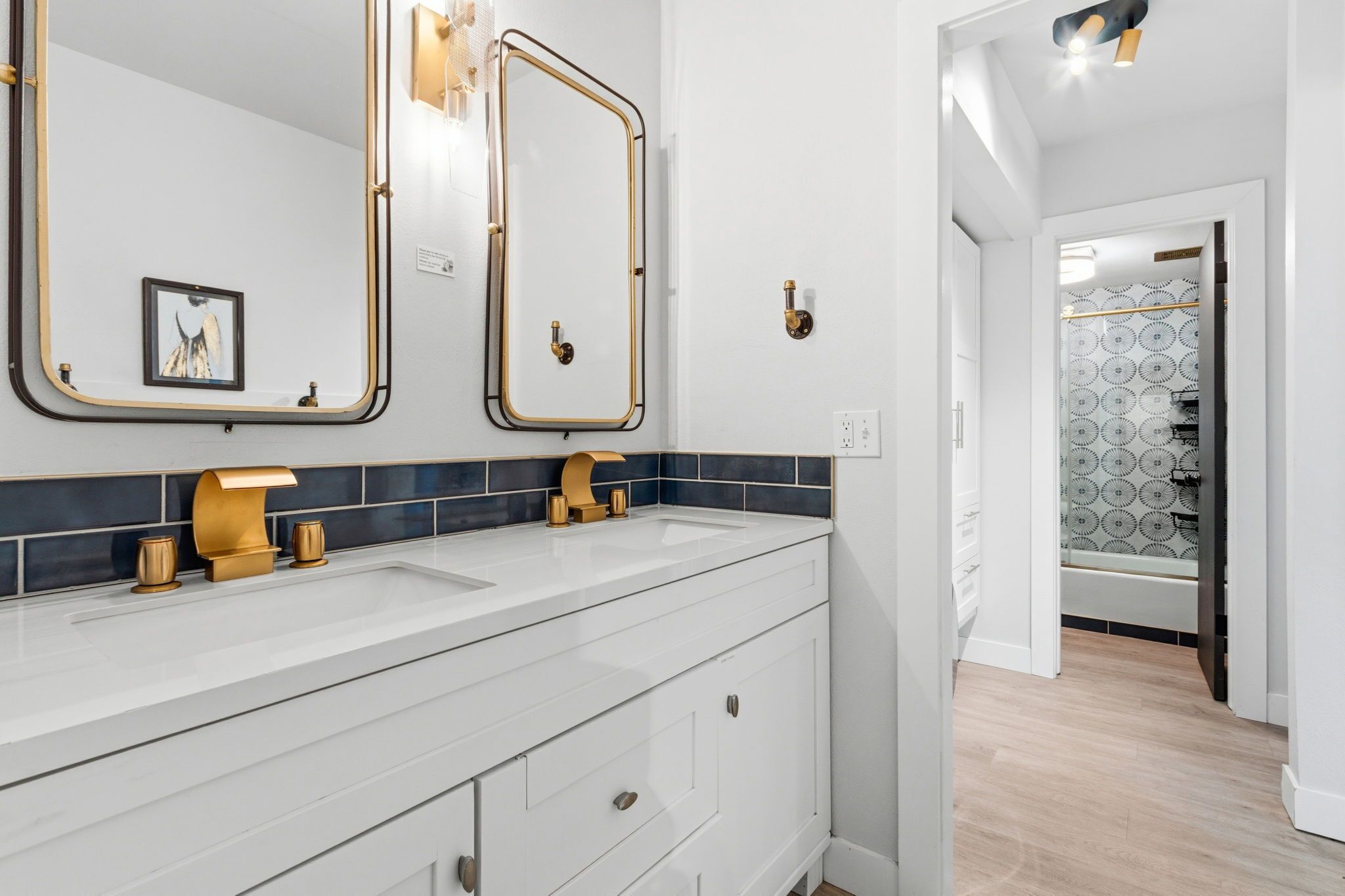 A modern bathroom with two sinks, gold fixtures, and a large mirror.