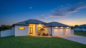 Une maison moderne à deux étages, dotée d’un garage, d’une pelouse bien entretenue et offrant une vue dégagée sur le ciel nocturne.