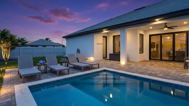 Une piscine avec des chaises longues, un patio couvert et une maison avec un toit plat.