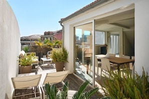 A balcony with outdoor seating, potted plants, and a sliding glass door leading to an interior dining area. - 3 bedrooms - hot tub - Downtown Cannes (Cannes)
