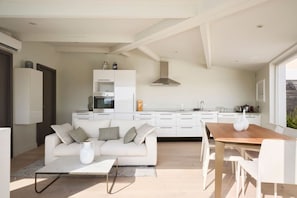 A modern kitchen with white cabinetry, a dining area with a wooden table and chairs, and a living room with a sofa and coffee table. - 3 bedrooms - hot tub - Downtown Cannes (Cannes)