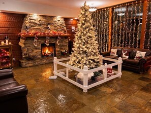 A cozy living room with a fireplace, a Christmas tree, and a leather sofa. - Snowshoe Village Great Views Sleeps 6 (Snowshoe)