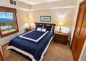 A bedroom with a bed, two bedside tables, a window, and a door. - Rimfire 205 Snowshoe Village Great Views Sleeps 6 (Snowshoe)