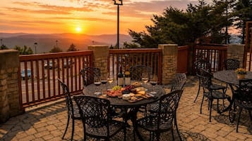 Un espacio de comedor al aire libre con una mesa redonda, sillas y vista al atardecer.