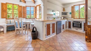 Una cocina con armarios de madera, horno empotrado y comedor con mesa y sillas.