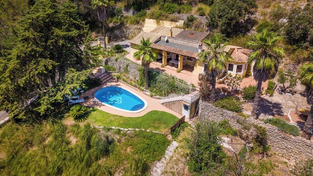 Vista aérea de una propiedad con piscina, patio y una pequeña casa de huéspedes.