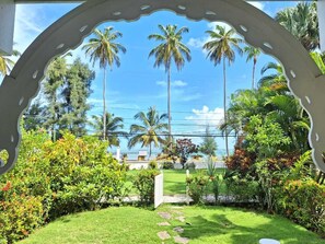 A garden with palm trees, a white gate, and a clear sky. - Rare Sea View Gem Steps from the Village for 4per (Las Terrenas)