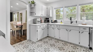 Une cuisine moderne avec des meubles blancs, un plan de travail noir et un sol à motifs.