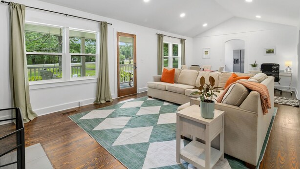 Un salon moderne avec un canapé, une table basse et une vue sur un jardin grâce à de grandes fenêtres.