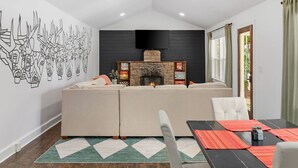 Un salon moderne avec un canapé d’angle, une cheminée et un téléviseur à écran plat fixé au mur.