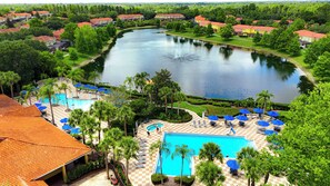 Ein Resort mit einem großen Swimmingpool, einem See und Blick auf umliegende Häuser.