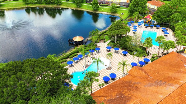 A resort with a swimming pool, lounge areas, and a pond.
