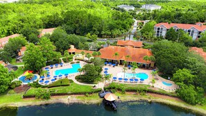 A resort with multiple swimming pools, a dock, and lush greenery.