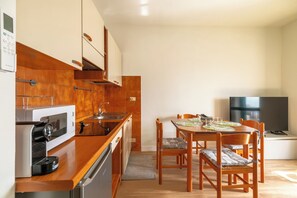 A compact kitchen with a microwave, stove, and sink, a dining table with chairs, and a TV in a separate room. - Casa Dreamo - One Bedroom Apartment, Sleeps 2 (Sarnico)