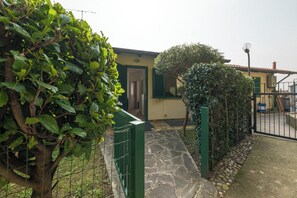 A building with a stone pathway leading to a door, surrounded by greenery and a metal gate. - Casa Dreamo - One Bedroom Apartment, Sleeps 2 (Sarnico)