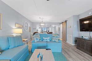 A living room with a sofa, a coffee table, and a television. - ⛱️Beachfront | Heated Swimming Pool | Caper Beach Club 313⛱️ (Fort Myers Beach)