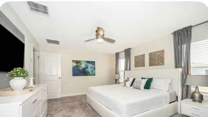 Ein Schlafzimmer mit einem Bett, Nachttischen, einem Deckenventilator und Kunstwerken an den Wänden.