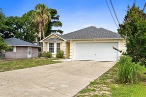 Einbungalow mit Garage, Vorgarten und einer Palme.