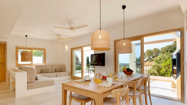 Ein modernes Interieur mit Essbereich, einer Couch und großen Fenstern.