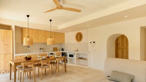 Eine moderne Küche mit Holzausbau, einem Esstisch mit Stühlen, einem Deckenventilator und einem runden Spiegel an der Wand.