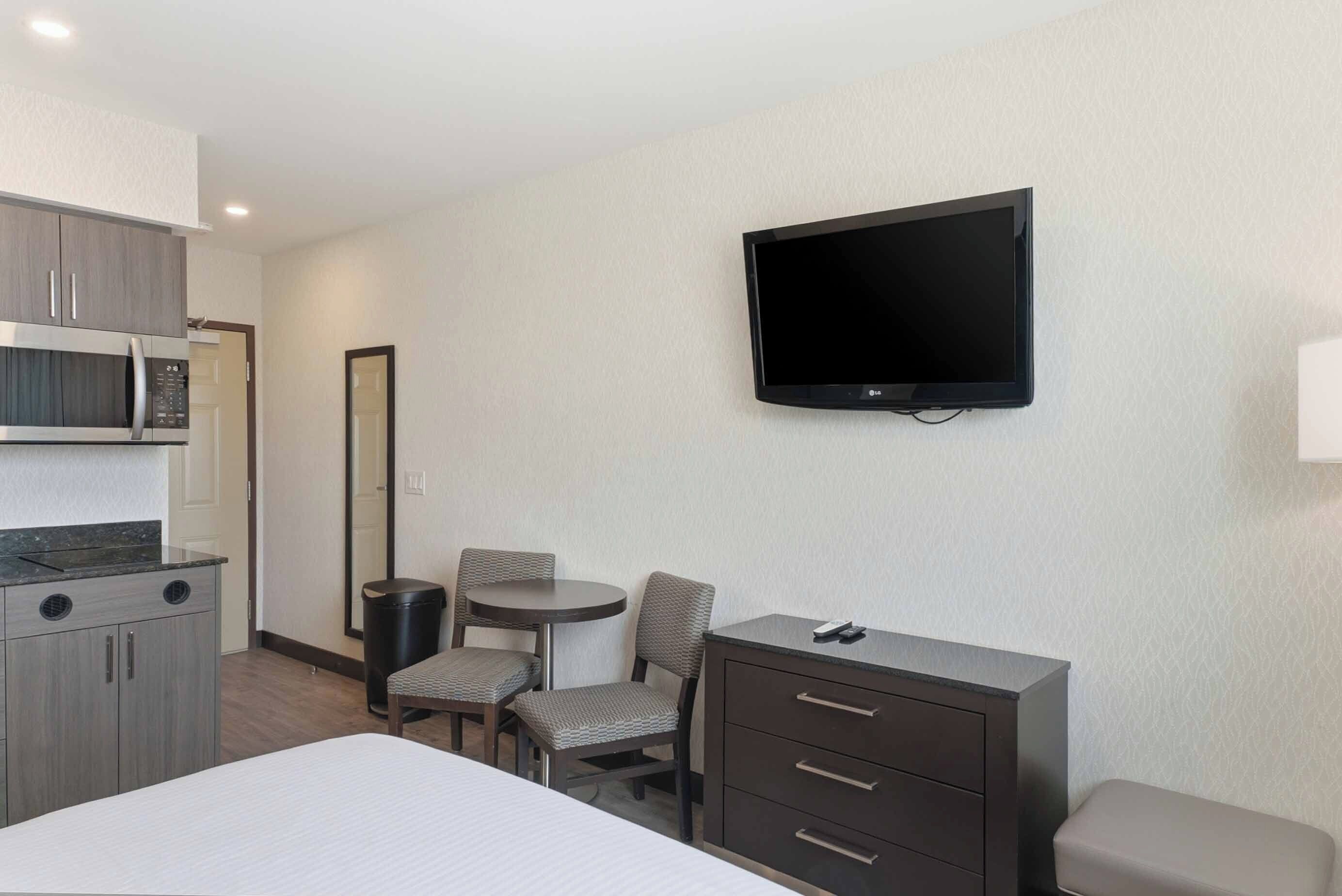 Une chambre d’hôtel équipée d’un lit, d’un bureau, d’une chaise, d’une télévision, d’un four à micro-ondes et d’un placard.