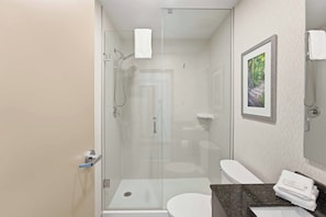 Een moderne badkamer met een douchecabine van glas, een wit toilet en een wastafel met een marmeren aanrecht.