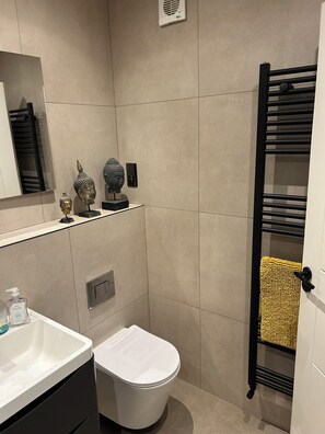 A modern bathroom with a toilet, sink, mirror, and towel rack.